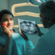 Female patient holding cheek in pain while dentist shows dental X-ray, indicating a potential dental abscess.