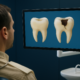 Patient viewing screen showing side-by-side images of dental erosion vs. cavities on tooth models.