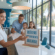 Smiling receptionist showing a sign for weekend dental appointments as a family enters, highlighting dentist open on Saturday near me.