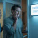 Man clutching his jaw in pain entering an emergency dentistry clinic at night, illustrating a search for an emergency dentist near me.