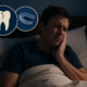 Man in bed experiencing jaw pain from teeth grinding with icons of a cracked tooth and mouthguard.