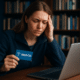 A worried woman holding a Medi-Cal card while researching dental options online.